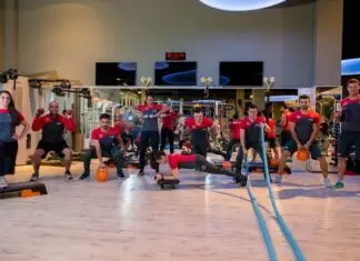 Como escolher uma academia com acompanhamento profissional de verdade? Instrutora corrige postura de aluna durante exercício com bola em academia.