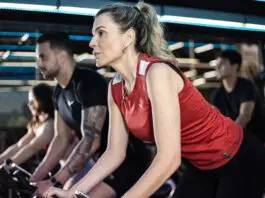 Como manter constância nos treinos mesmo com rotina corrida Alunos praticando spinning em academia moderna, com foco e intensidade durante treino coletivo, mesmo em rotina agitada.