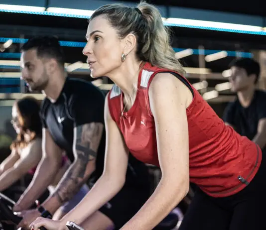 Alunos praticando spinning em academia moderna, com foco e intensidade durante treino coletivo, mesmo em rotina agitada.